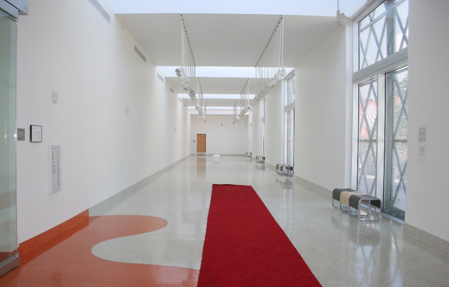 Long gallery hallway with white walls and red carpet